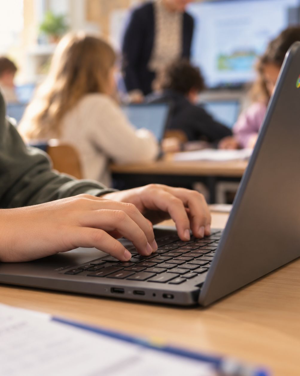 Close-up van handen die typen op een Chromebook, met een werkblad op tafel